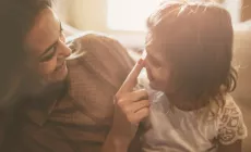 mother touching little girl's face as they smile at each other