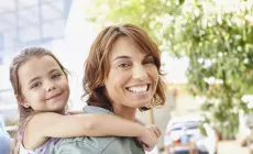 woman smiling holding daughter on her back