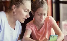 mother and tween daughter look at phone