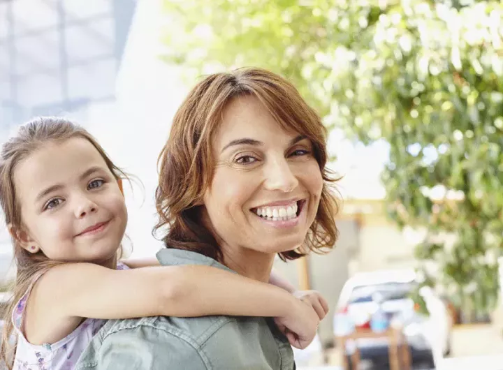 woman smiling holding daughter on her back