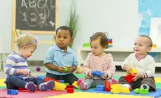 four toddlers play with toy building blocks